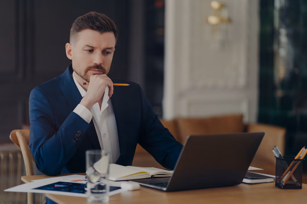 serious-male-entrepreneur-holds-chin-makes-notes-diary-works-laptop-computer-makes-money-online-dressed-formally-writes-information-confident-managing-director-involved-working-process_95891-4864